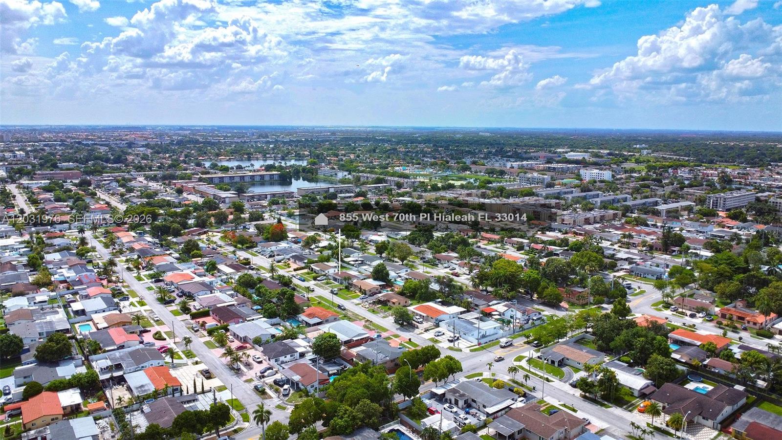 An aerial view shows a residential neighborhood with single-family homes, streets, and a distant lake — 855 W 70th Pl, Hialeah FL 33014, HIALEAH, FL