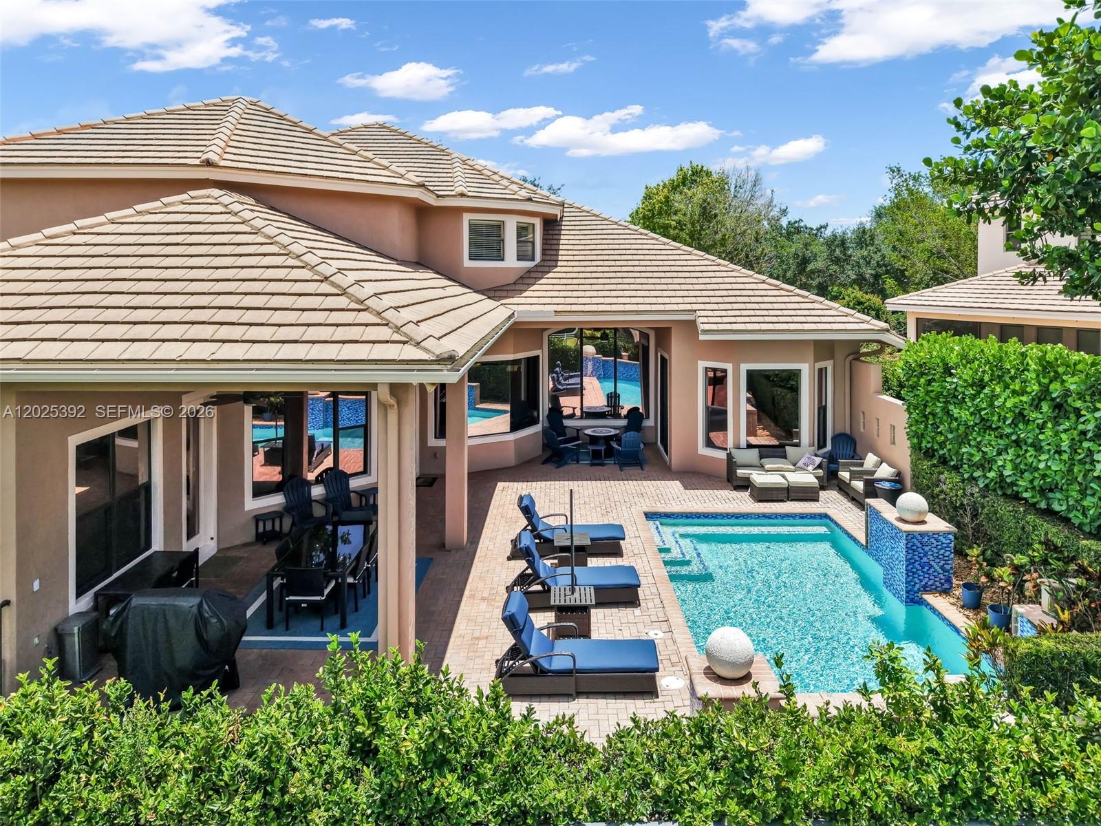 An aerial view of a house exterior featuring a swimming pool, patio, and lounge chairs — 8891 Equus Cir, Boynton Beach FL 33472, BOYNTON BEACH, FL