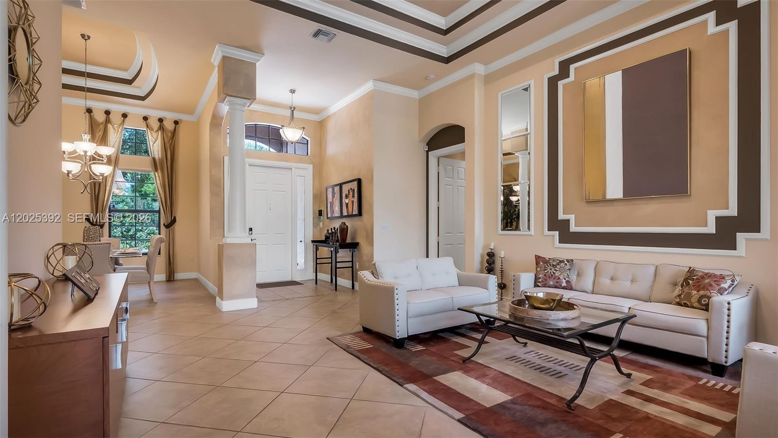 A spacious living room features high ceilings, tile floors, and a large wall-mounted painting — 8891 Equus Cir, Boynton Beach FL 33472, BOYNTON BEACH, FL