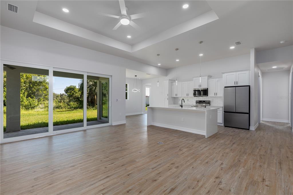 An open-concept kitchen and living area features white cabinetry, a center island, and sliding doors — 521 NW 5TH STREET, CAPE CORAL, FL
