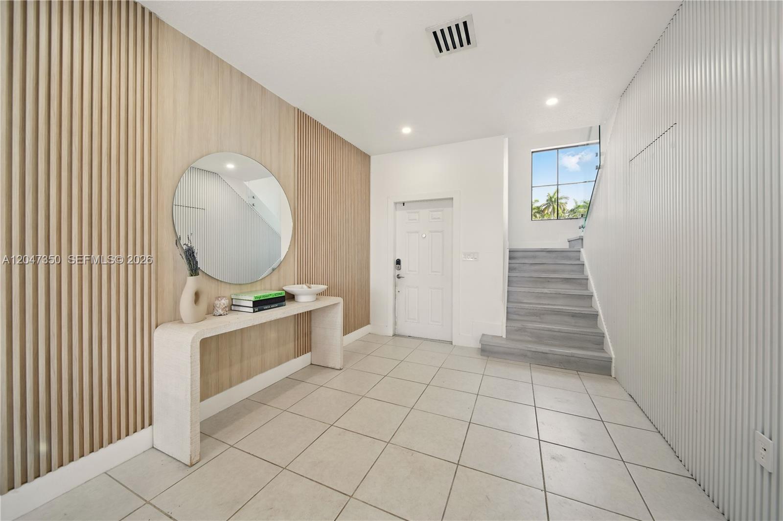 An entryway features a wood-slat accent wall, a console table, and stairs leading upward — 10269 SW 231st Ln # 0, Miami FL 33190, MIAMI, FL