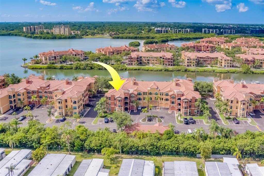 An aerial view shows a multi-story apartment complex with a yellow arrow pointing downward — 2741 VIA CIPRIANI UNIT 930A, CLEARWATER, FL