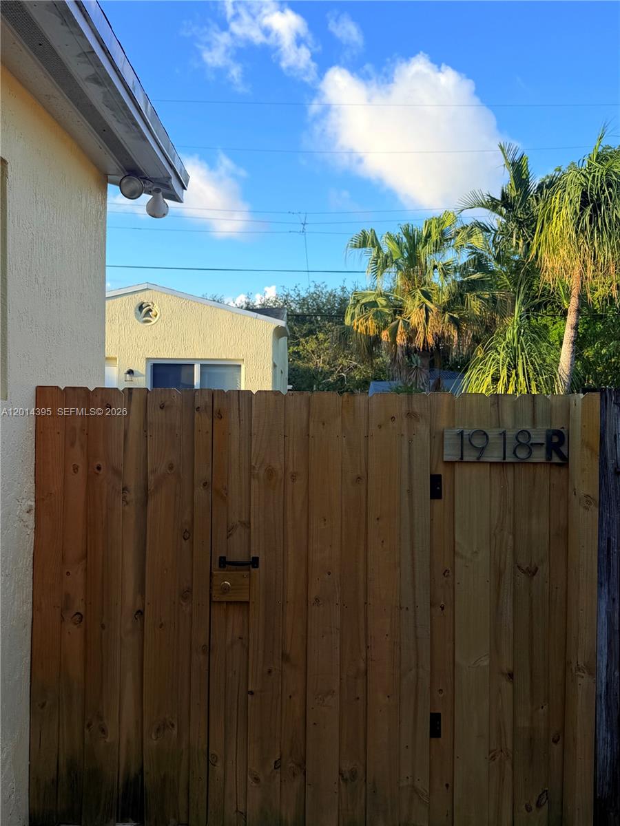 A wooden gate with the address 1918-R stands in front of a yellow house — 1918 Adams St Rear, Hollywood FL 33020, HOLLYWOOD, FL