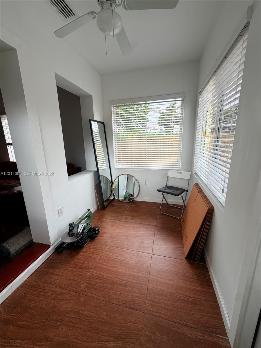 A sunroom features wood-look tile flooring, white walls, two windows with blinds, and a ceiling fan — 1918 Adams St Rear, Hollywood FL 33020, HOLLYWOOD, FL