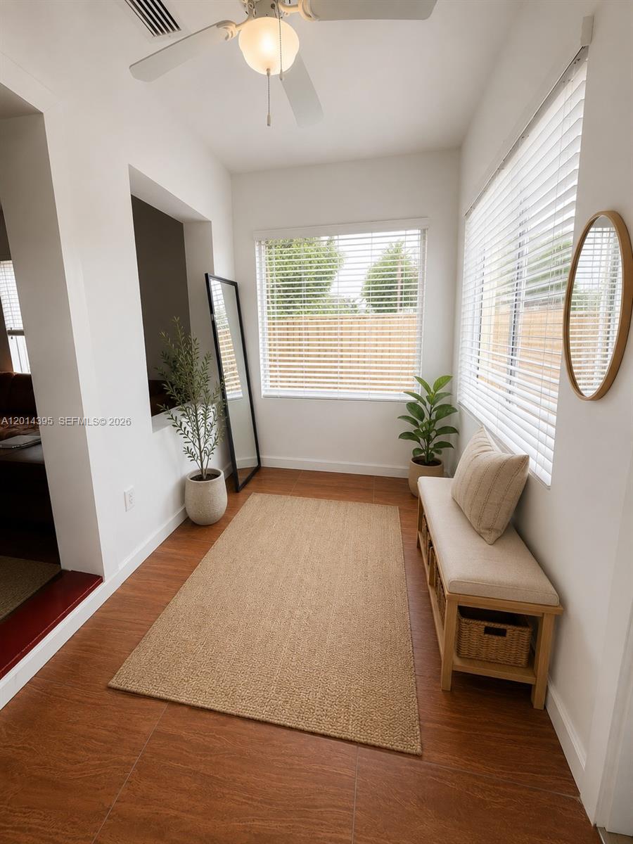 A sunroom features wood-look tile flooring, a bench with storage, and two potted plants — 1918 Adams St Rear, Hollywood FL 33020, HOLLYWOOD, FL