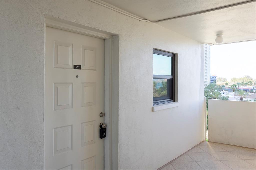 A white apartment door with a lockbox and a window on a covered outdoor walkway — 1230 GULF BOULEVARD UNIT 608, CLEARWATER BEACH, FL