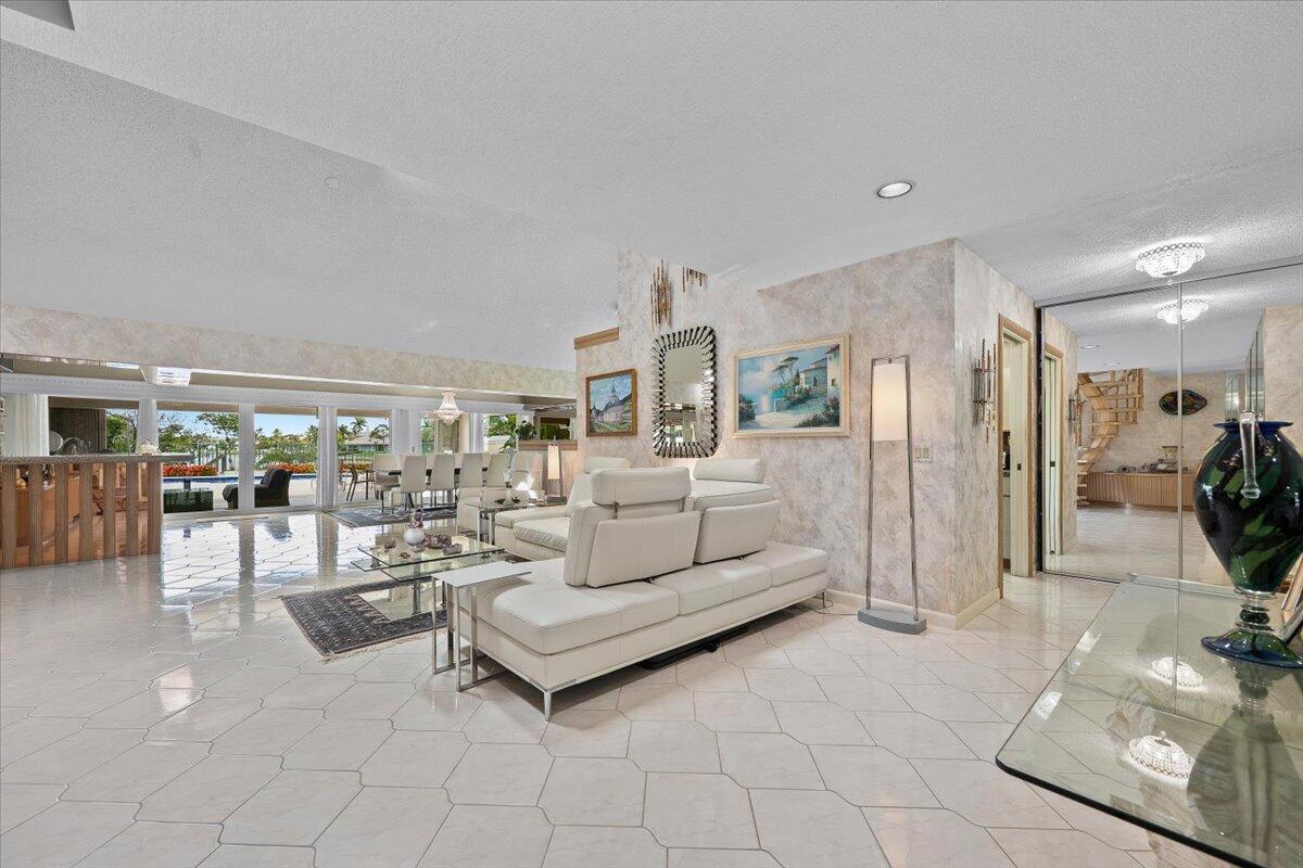 A bright living room features white tile floors, a white sectional sofa, and glass doors — 352 River Edge Road, Jupiter FL 33477, JUPITER, FL