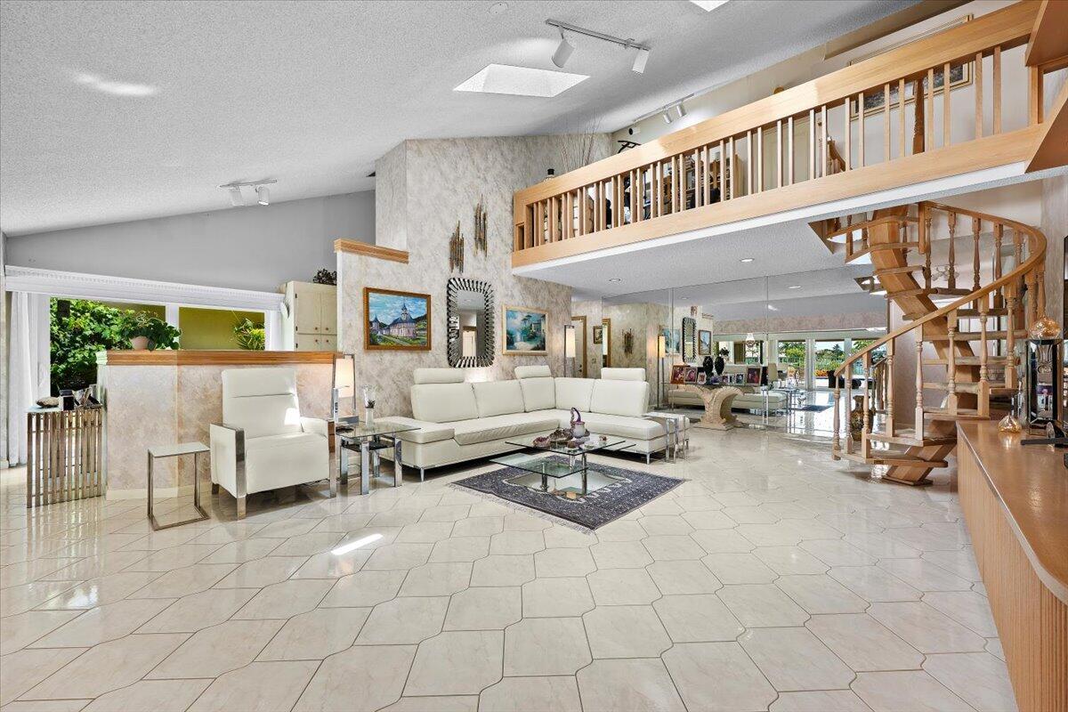 A spacious living room features a spiral staircase, a loft balcony, and light-colored tile flooring — 352 River Edge Road, Jupiter FL 33477, JUPITER, FL