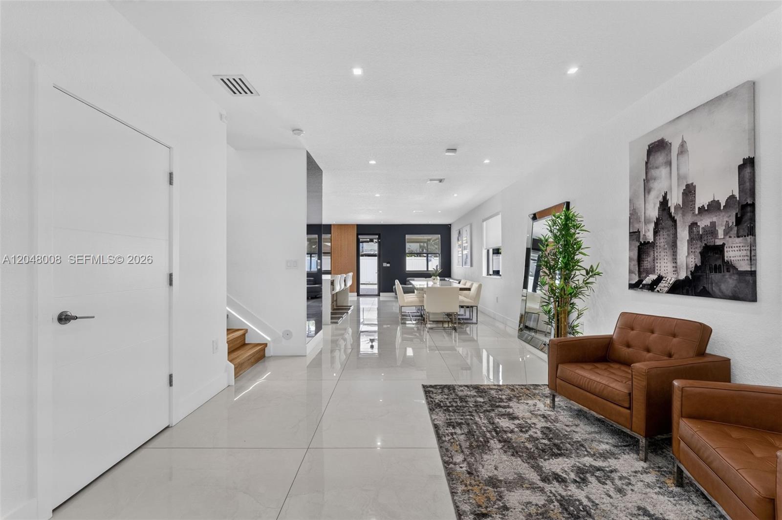 A modern living and dining area features white tile floors, leather chairs, and stairs — 11024 W 35th Ln, Hialeah FL 33018, HIALEAH, FL