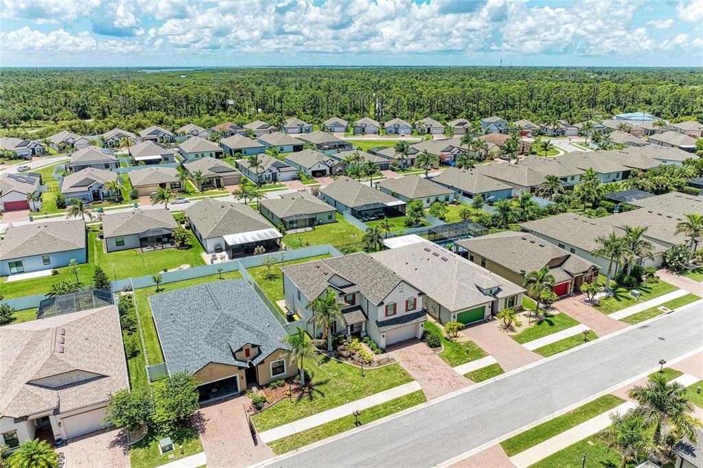 An aerial view shows a suburban neighborhood with single-family homes, paved streets, and green lawns — 2084 LA PALMA AVENUE, PORT CHARLOTTE, FL