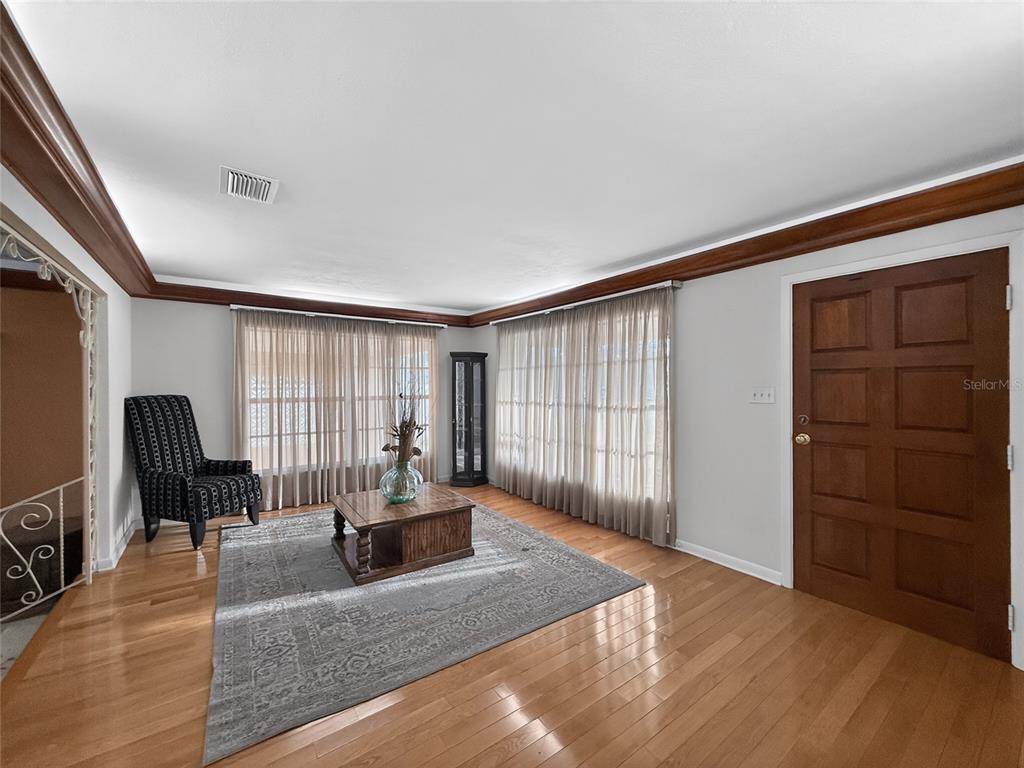 A living room with hardwood floors, a patterned area rug, a coffee table, and a door — 305 N GLEN AVENUE, TAMPA, FL
