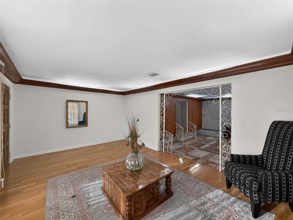 A living room features hardwood floors, a patterned rug, a coffee table, and decorative metal archways — 305 N GLEN AVENUE, TAMPA, FL