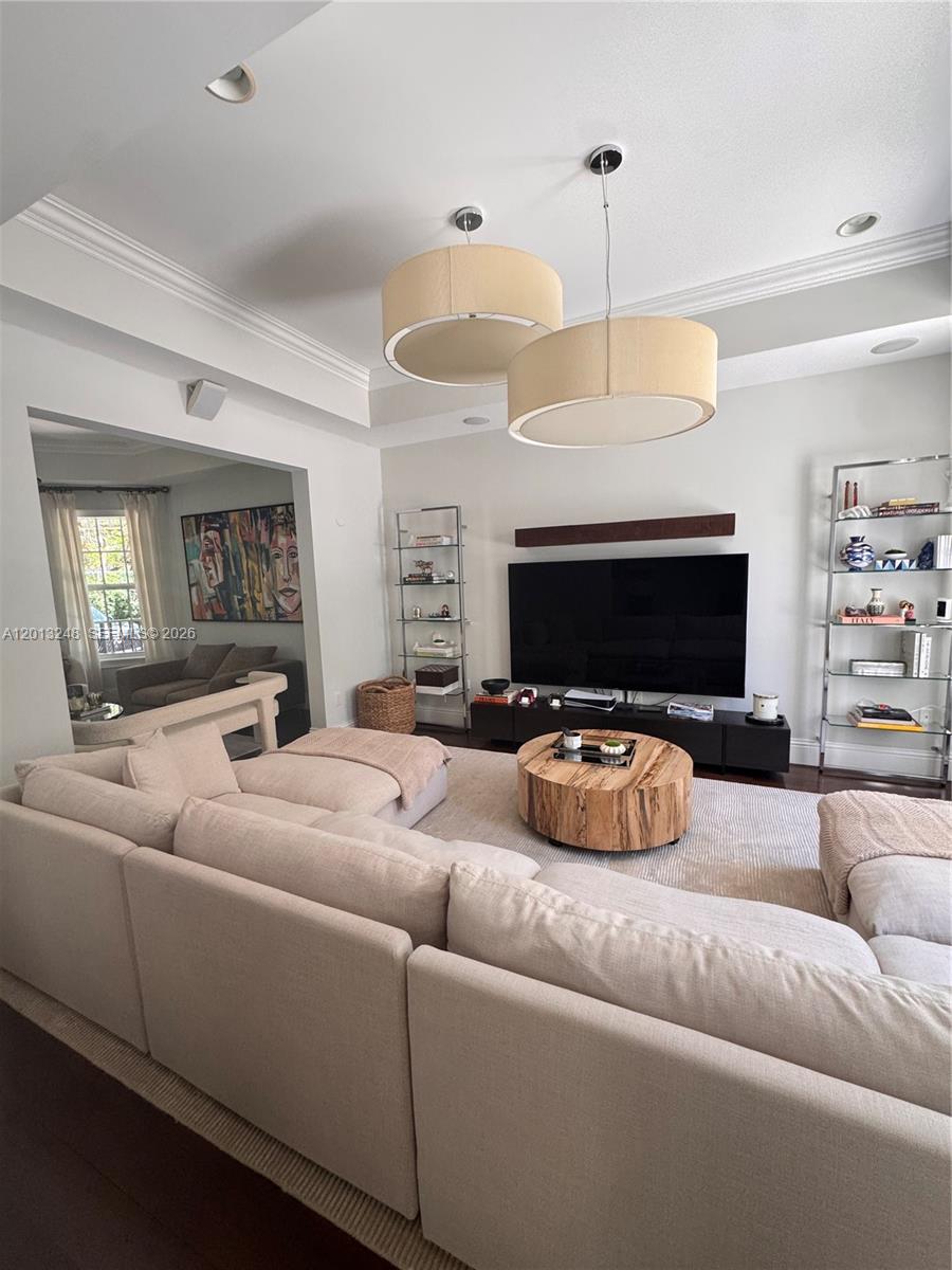 A living room features a large sectional sofa, a circular wooden coffee table, and shelving — 5000 SW 73rd Ter, Miami FL 33143, MIAMI, FL