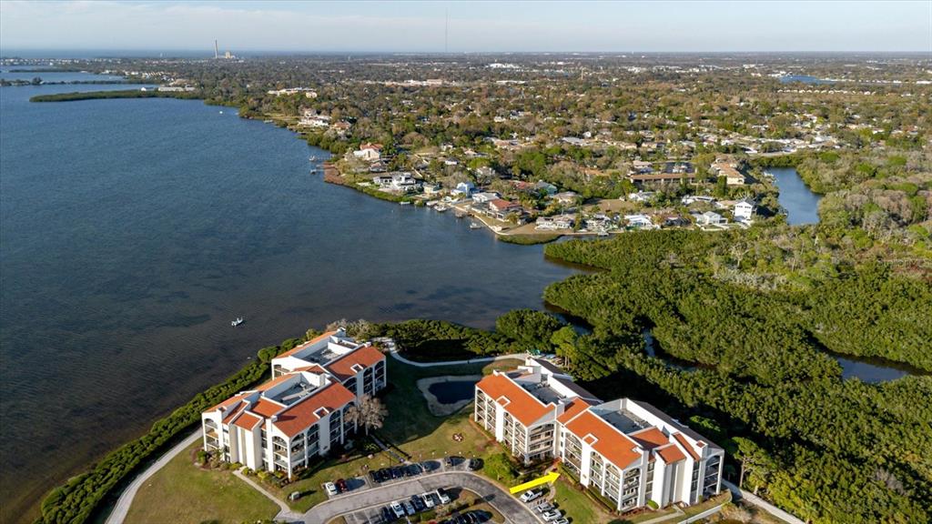 An aerial view shows two multi-story apartment buildings situated on a waterfront peninsula — 208 MARINER DRIVE UNIT 208, TARPON SPRINGS, FL