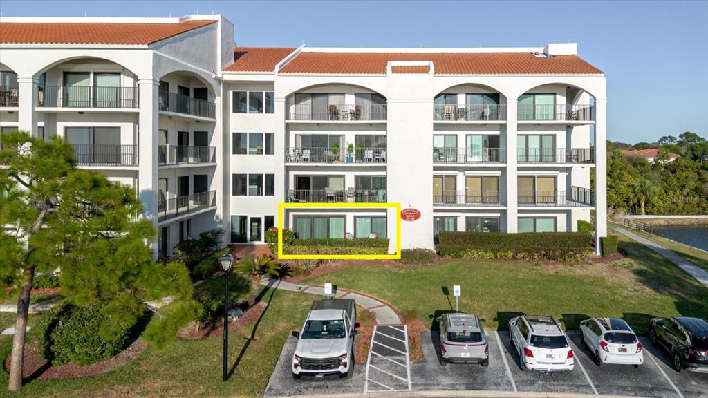An exterior view of a multi-story apartment building with a ground-floor unit highlighted in yellow — 208 MARINER DRIVE UNIT 208, TARPON SPRINGS, FL