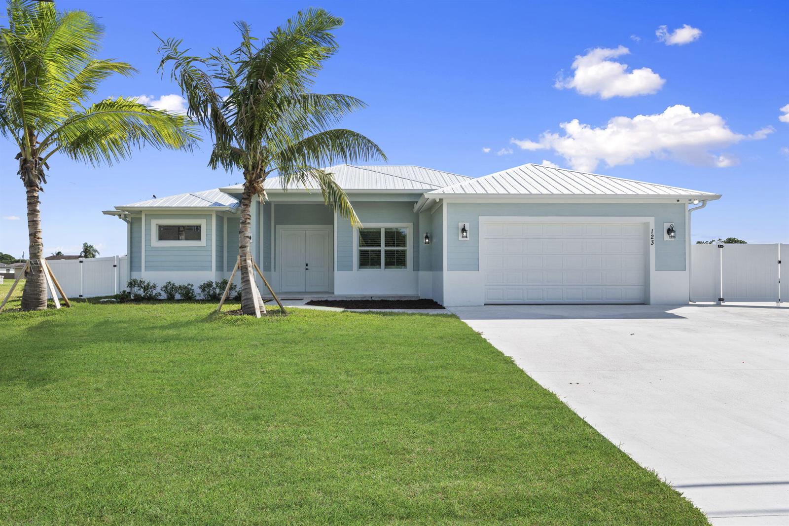 A light blue, single-story house with a white metal roof and a two-car garage — 3834 NE Barbara Drive, Jensen Beach FL 34957, JENSEN BEACH, FL