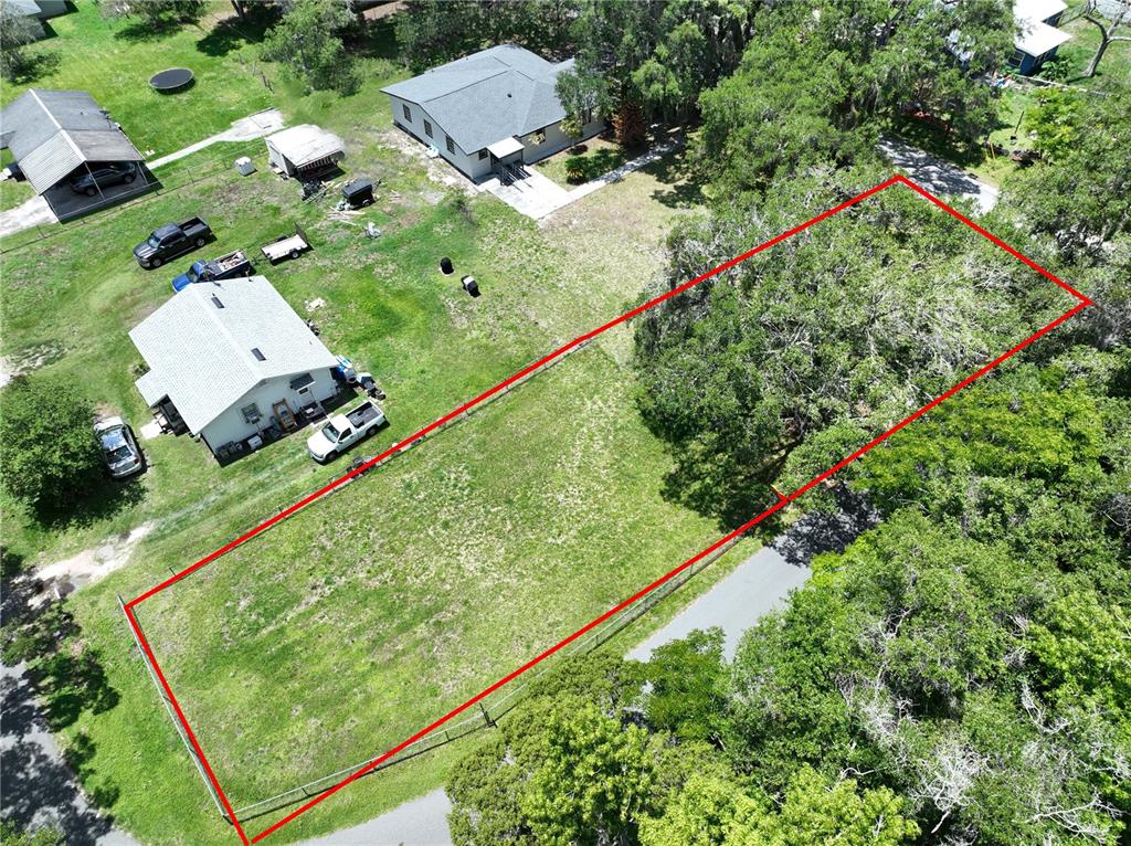An aerial view shows a rectangular, fenced-in grassy lot bordered by trees and nearby houses — 0 EAST AVE, BROOKSVILLE, FL