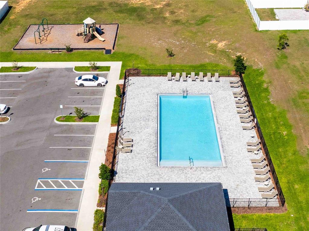 An aerial view shows a swimming pool, lounge chairs, a playground, and a parking lot — 11644 JUDICIAL COURT, DADE CITY, FL