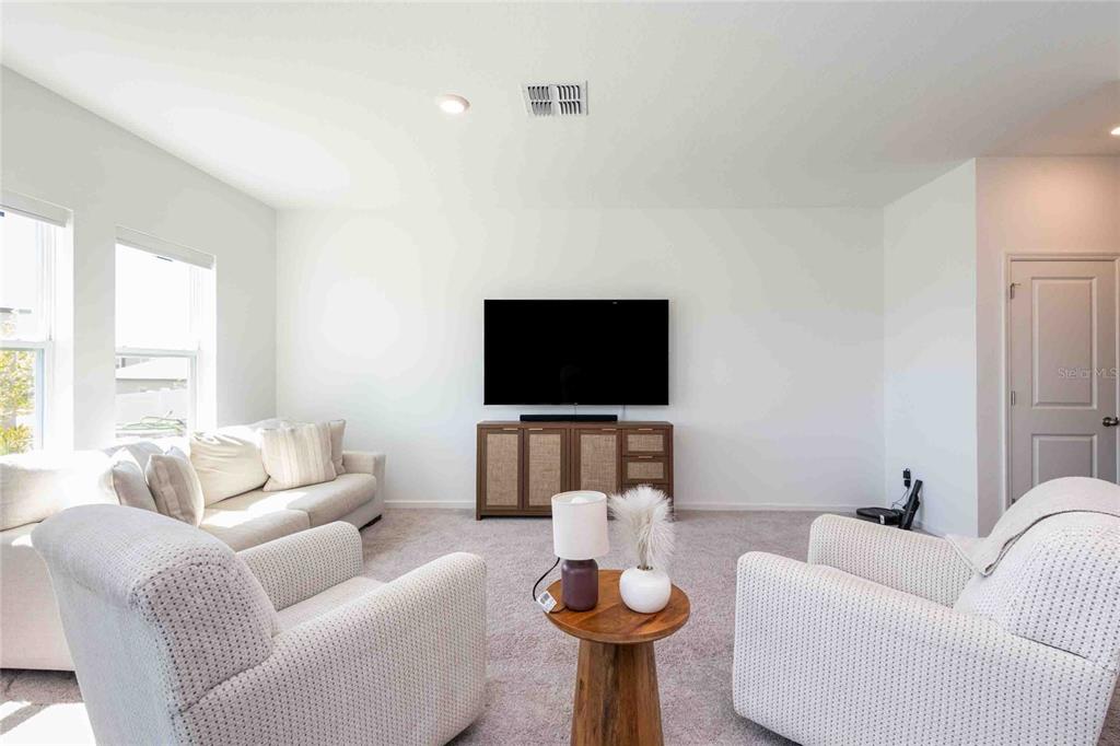 A living room features a wall-mounted television above a wooden console and light-colored furniture — 11644 JUDICIAL COURT, DADE CITY, FL