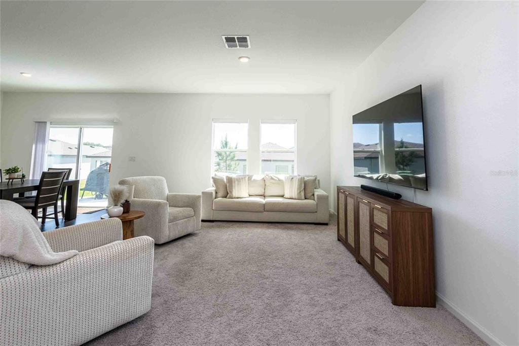 A living room features a wall-mounted television, a wooden media console, and neutral-toned furniture — 11644 JUDICIAL COURT, DADE CITY, FL