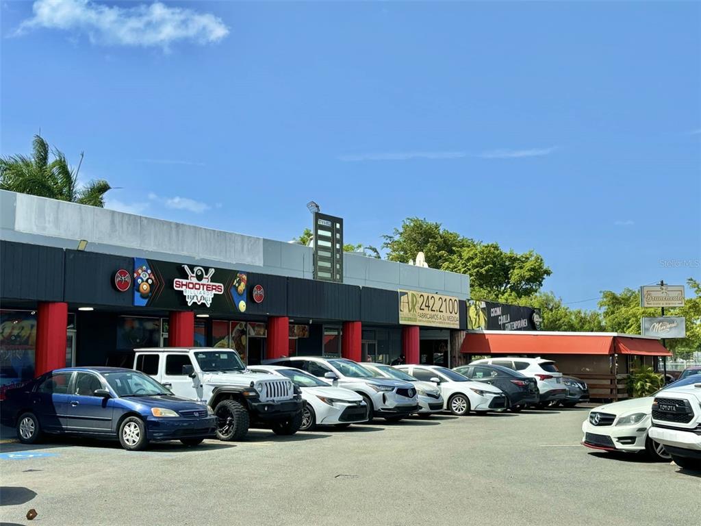 A commercial building with multiple storefronts and a parking lot filled with various vehicles — 1 BOULEVARD DE PALMAS, CATANO, PR