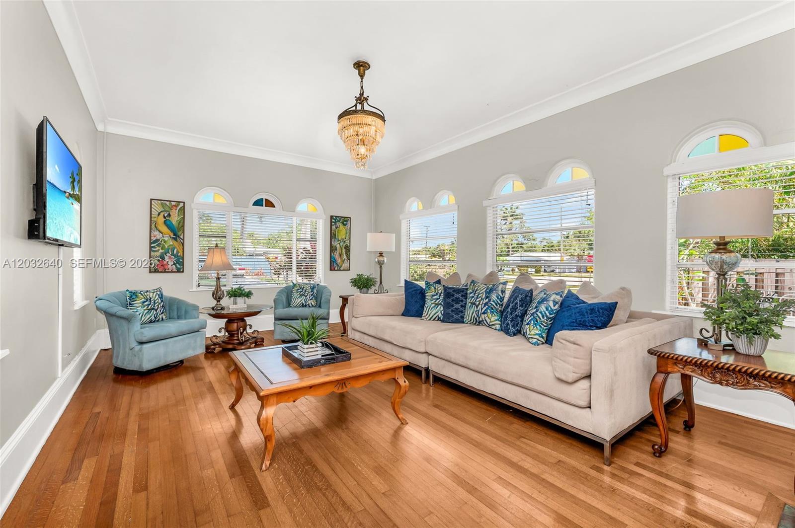 A living room features hardwood floors, a large beige sofa, two blue armchairs, and windows — 219 S 17th Ave S, Lake Worth FL 33460, LAKE WORTH, FL