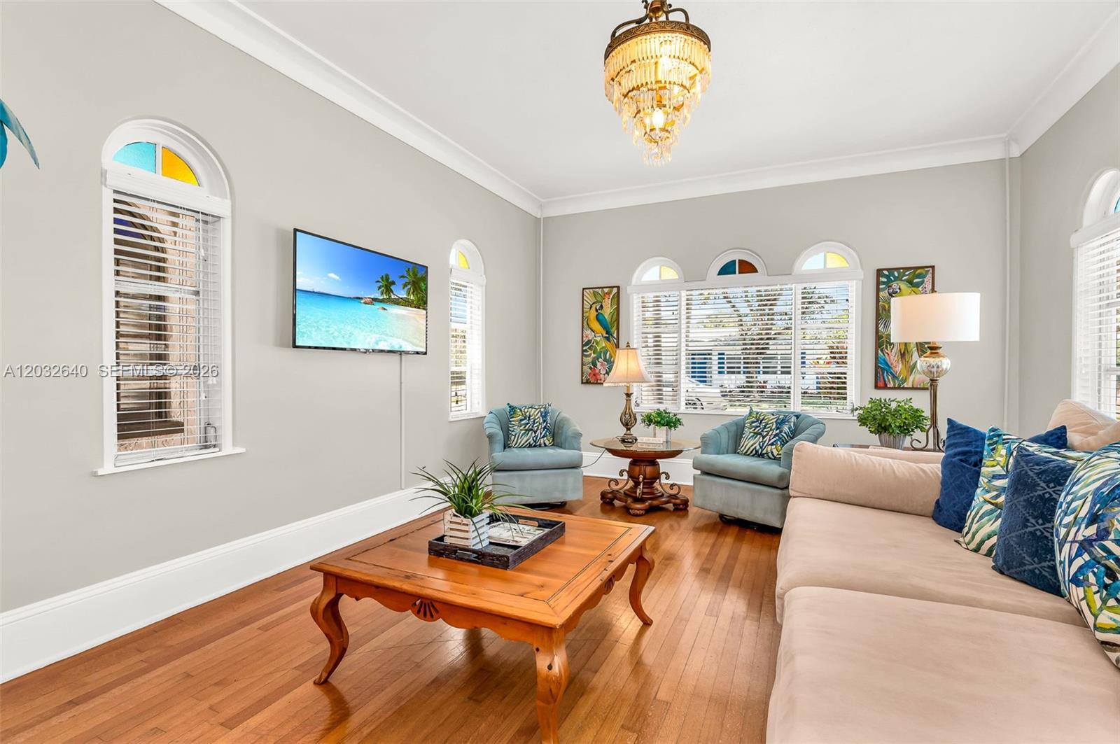 A living room features a beige sofa, two blue armchairs, a wooden coffee table, and a chandelier — 219 S 17th Ave S, Lake Worth FL 33460, LAKE WORTH, FL