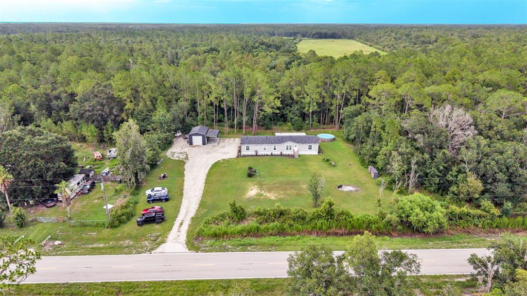 An aerial view shows a single-story house with a detached garage and pool on a lot — 12615 OLD DADE CITY ROAD, KATHLEEN, FL