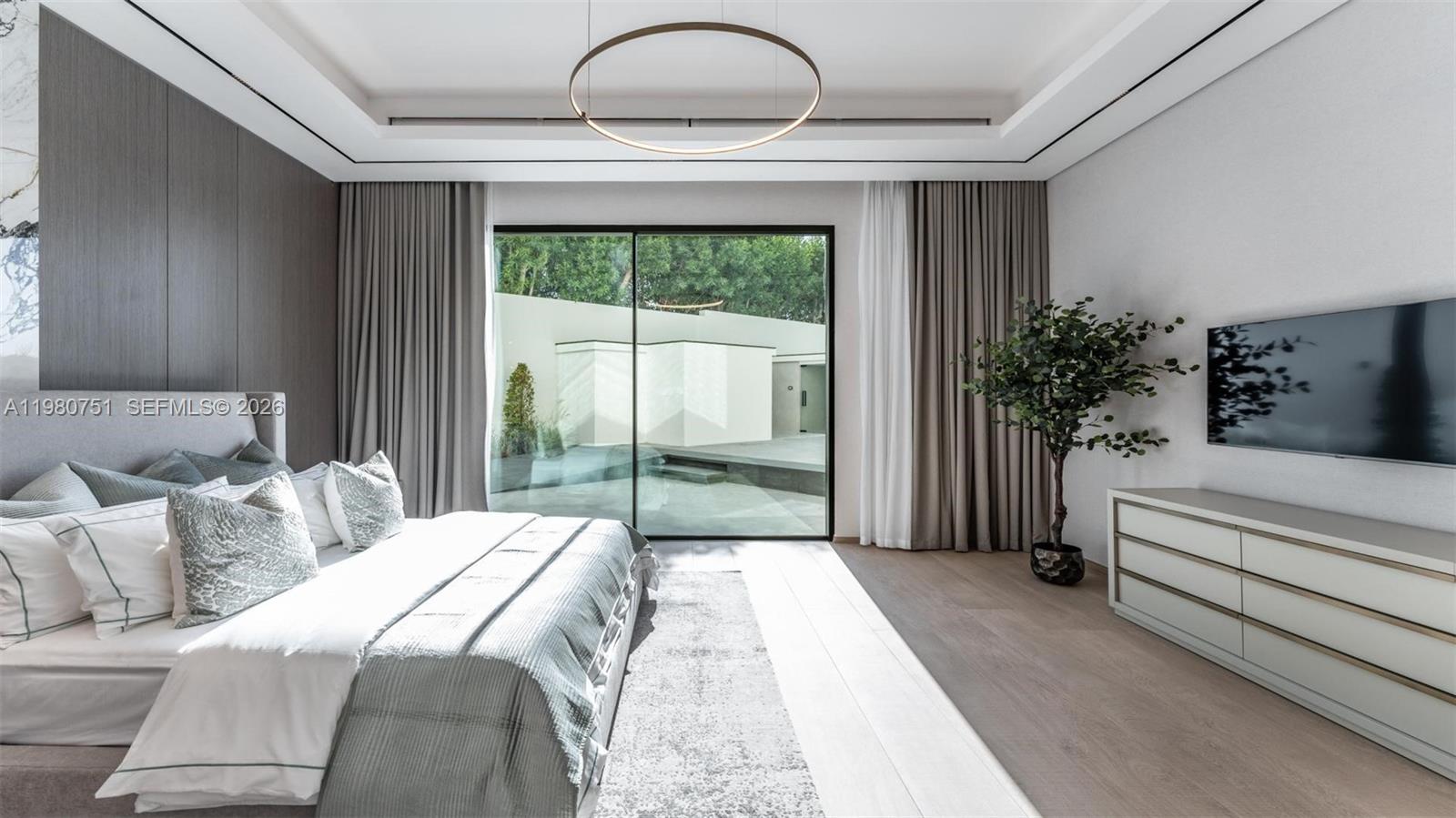 A modern bedroom features a large bed, a wall-mounted television, and floor-to-ceiling glass doors — 15 Sector W Road, Dubai, FL