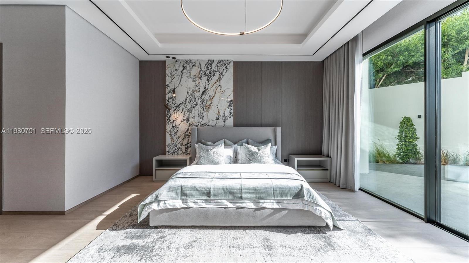 A modern bedroom features a marble accent wall, gray upholstered bed, and floor-to-ceiling glass doors — 15 Sector W Road, Dubai, FL