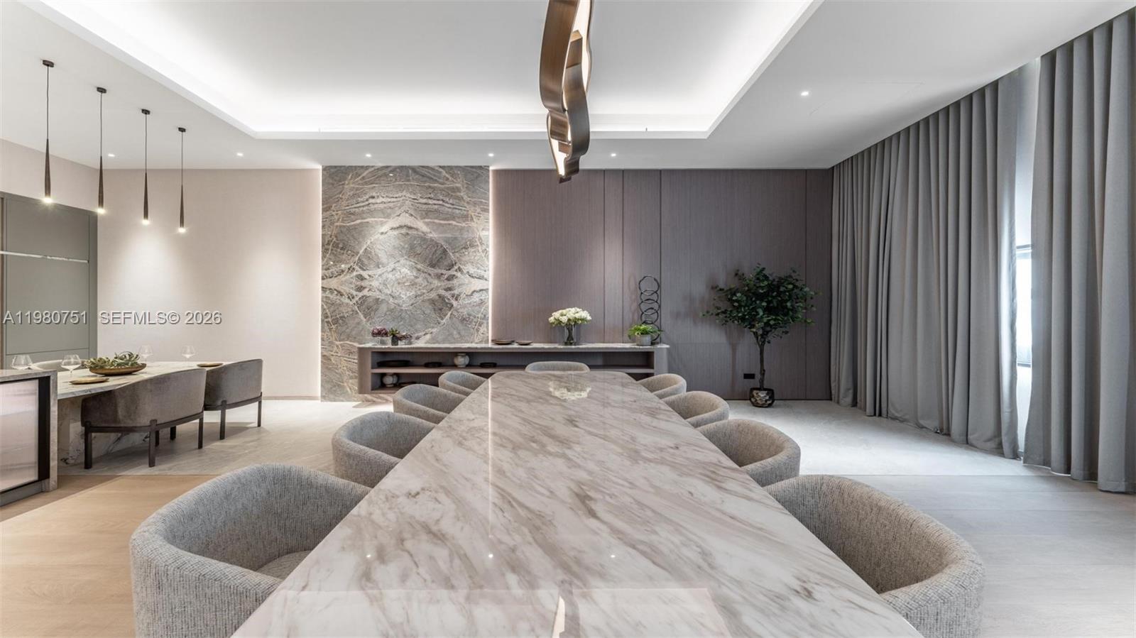 A modern dining room features a long marble table, upholstered chairs, and stone wall accents — 15 Sector W Road, Dubai, FL