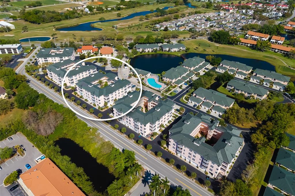 An aerial view shows a multi-story apartment complex with green roofs and a swimming pool — 1522 GONDOLA PARK DRIVE UNIT 1522, VENICE, FL