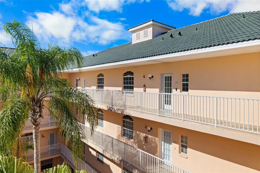 An exterior view of a multi-story apartment building with balconies and a green roof — 1522 GONDOLA PARK DRIVE UNIT 1522, VENICE, FL