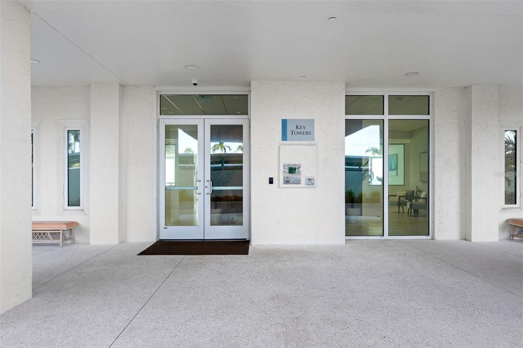 The exterior entrance of a building features glass double doors and a white facade — 1750 BENJAMIN FRANKLIN DRIVE UNIT 8D, SARASOTA, FL