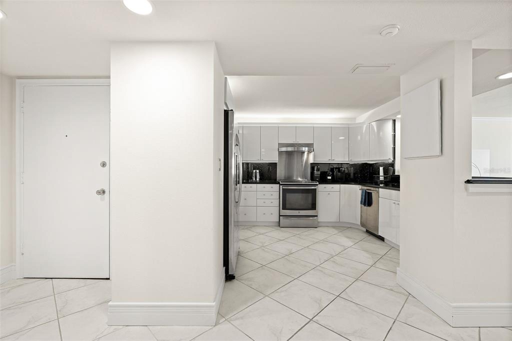 A kitchen with white cabinets, stainless steel appliances, and light-colored tile flooring — 1750 BENJAMIN FRANKLIN DRIVE UNIT 8D, SARASOTA, FL