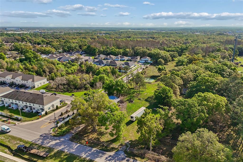 An aerial view shows a residential neighborhood bordering a large, wooded lot with a trailer — 6213 ORIENT ROAD, TAMPA, FL