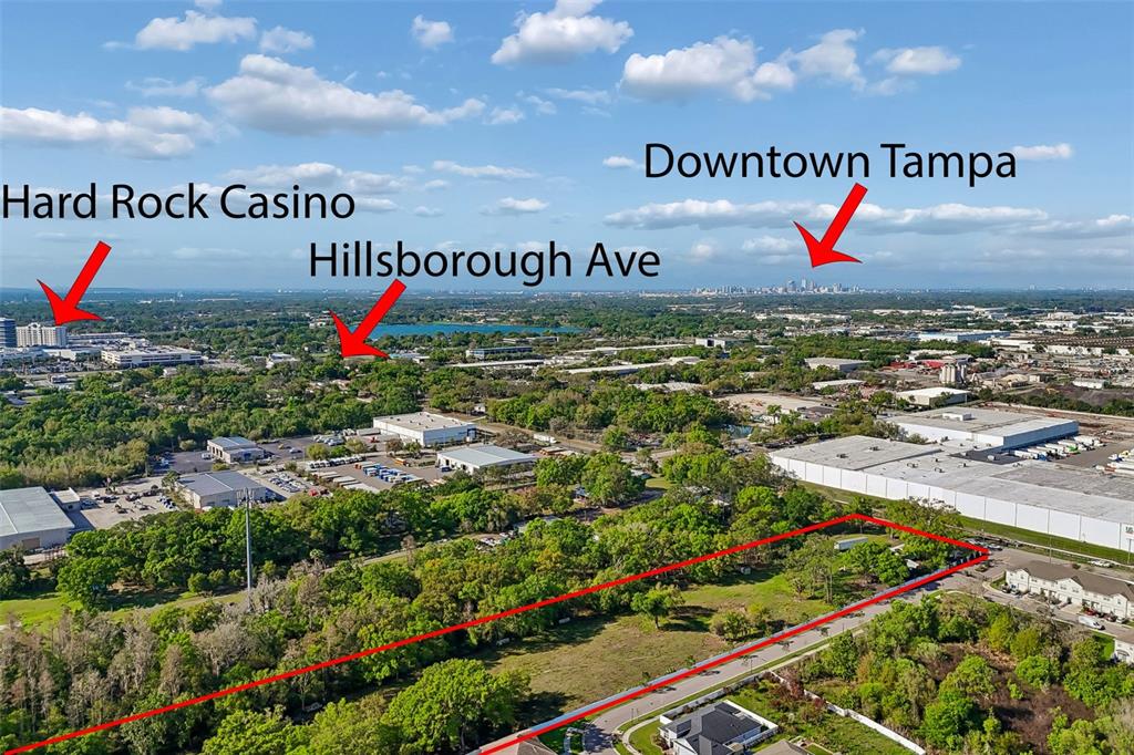 This aerial view shows a vacant, tree-lined lot outlined in red near industrial buildings — 6213 ORIENT ROAD, TAMPA, FL
