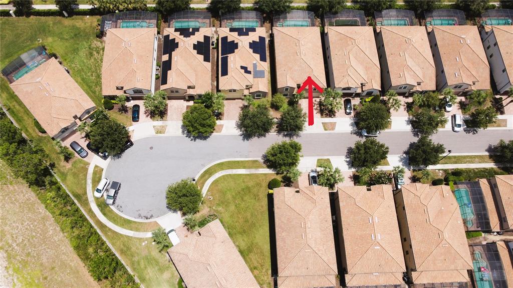 An aerial view shows a suburban neighborhood with houses, swimming pools, and a red arrow — 2183 TRIPOLI CT, KISSIMMEE, FL