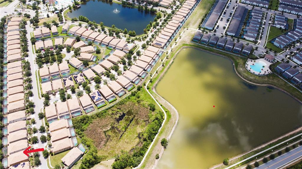 An aerial view shows a residential neighborhood with townhomes, a large pond, and green space — 2183 TRIPOLI CT, KISSIMMEE, FL