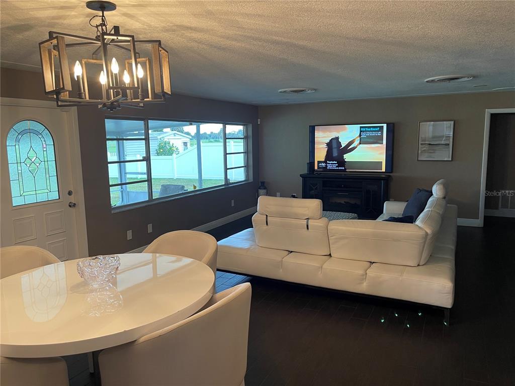 A living room and dining area with white furniture, dark wood floors, and a chandelier — 2101 PALM BOULEVARD, MELBOURNE, FL