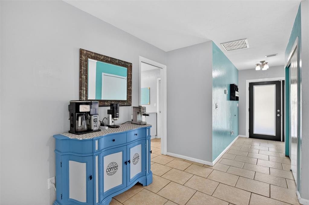 A bright hallway features a blue coffee station cabinet, tiled floors, and a glass-paneled door — 1305 SE 37TH TERRACE, CAPE CORAL, FL