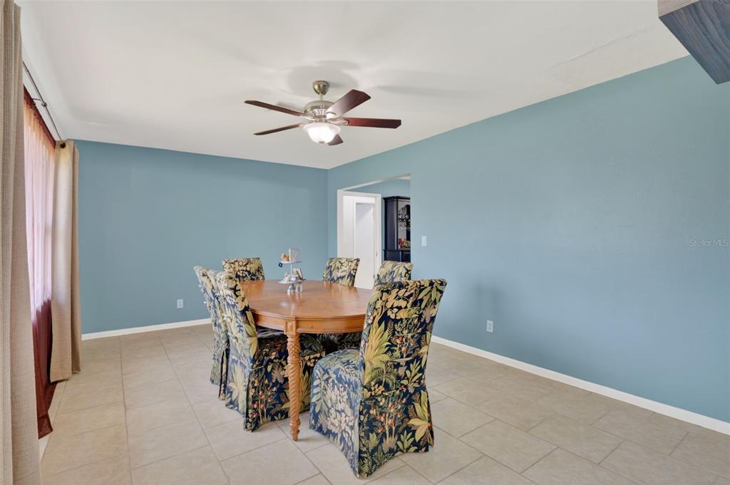 A dining room with blue walls, tile flooring, a wooden table, and patterned chairs — 1305 SE 37TH TERRACE, CAPE CORAL, FL