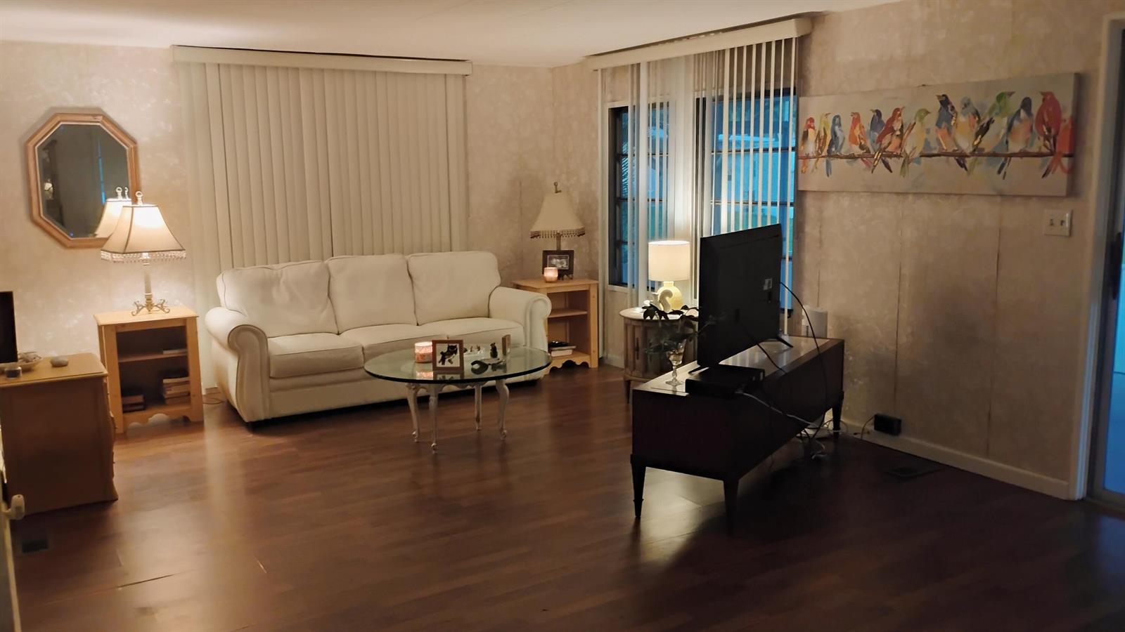 A living room features a white sofa, glass coffee table, television, and wood-look flooring — 20911 Sunrise Drive, Boca Raton FL 33433, BOCA RATON, FL