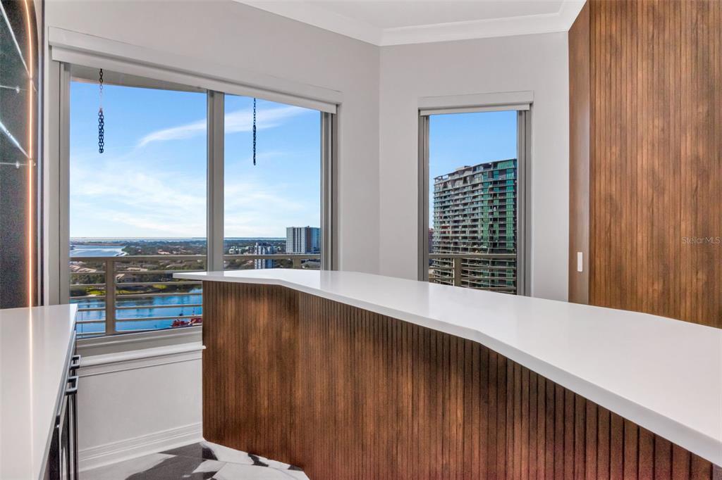 A modern bar area features a white countertop, wood-paneled cabinetry, and views of the water — 1209 E CUMBERLAND AVENUE UNIT 1701, TAMPA, FL
