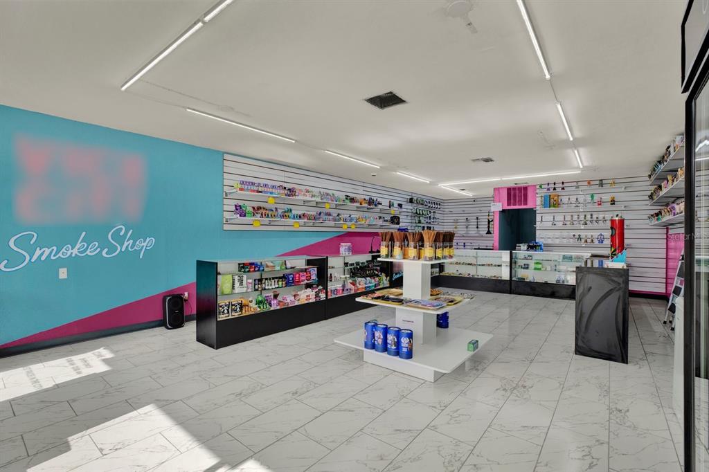 The interior of a smoke shop features white tiled floors, wall-mounted shelving, and display counters — N 49TH, PINELLAS PARK, FL