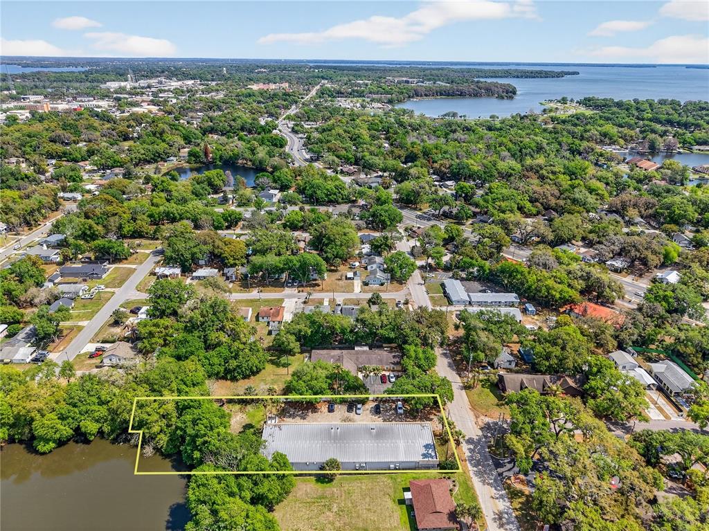An aerial view shows a rectangular commercial building situated next to a body of water — 1314 SUMTER STREET, LEESBURG, FL