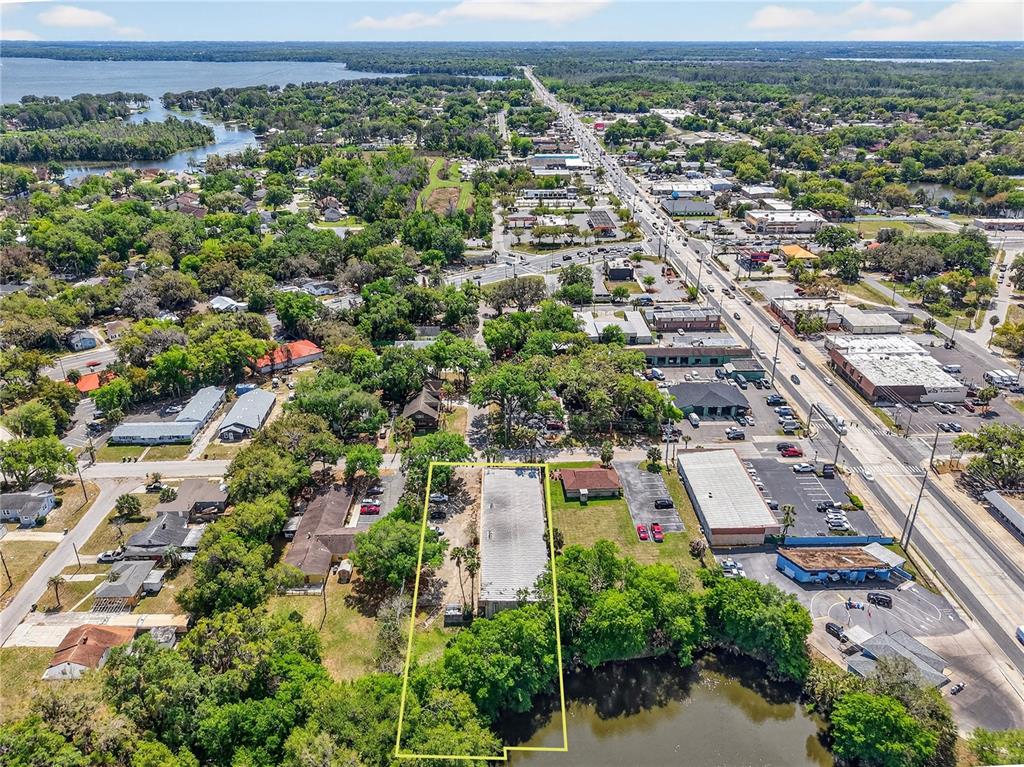 An aerial view shows a rectangular commercial building highlighted by a yellow outline near water — 1314 SUMTER STREET, LEESBURG, FL