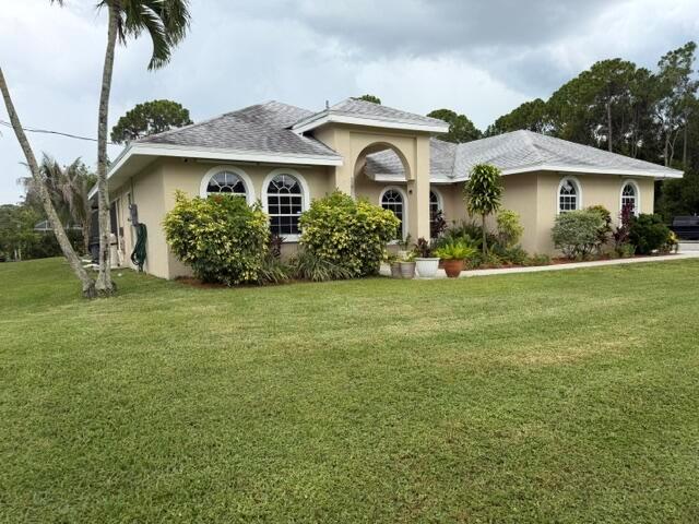 A single-story tan stucco house with a gray shingled roof and arched windows — 16304 Orange Boulevard, FL 33470, FL