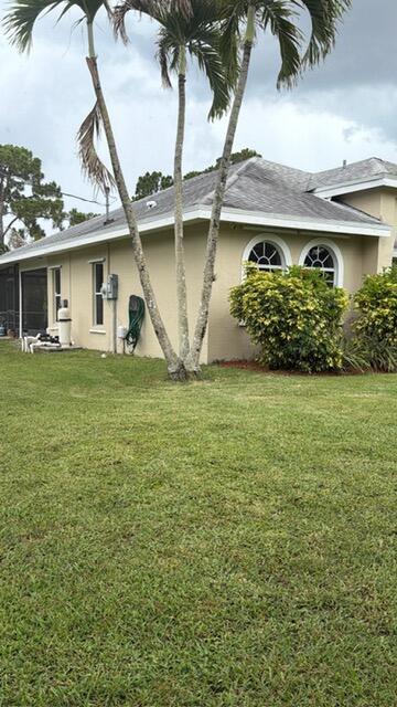 A tan house with a gray shingled roof and arched windows sits behind palm trees — 16304 Orange Boulevard, FL 33470, FL