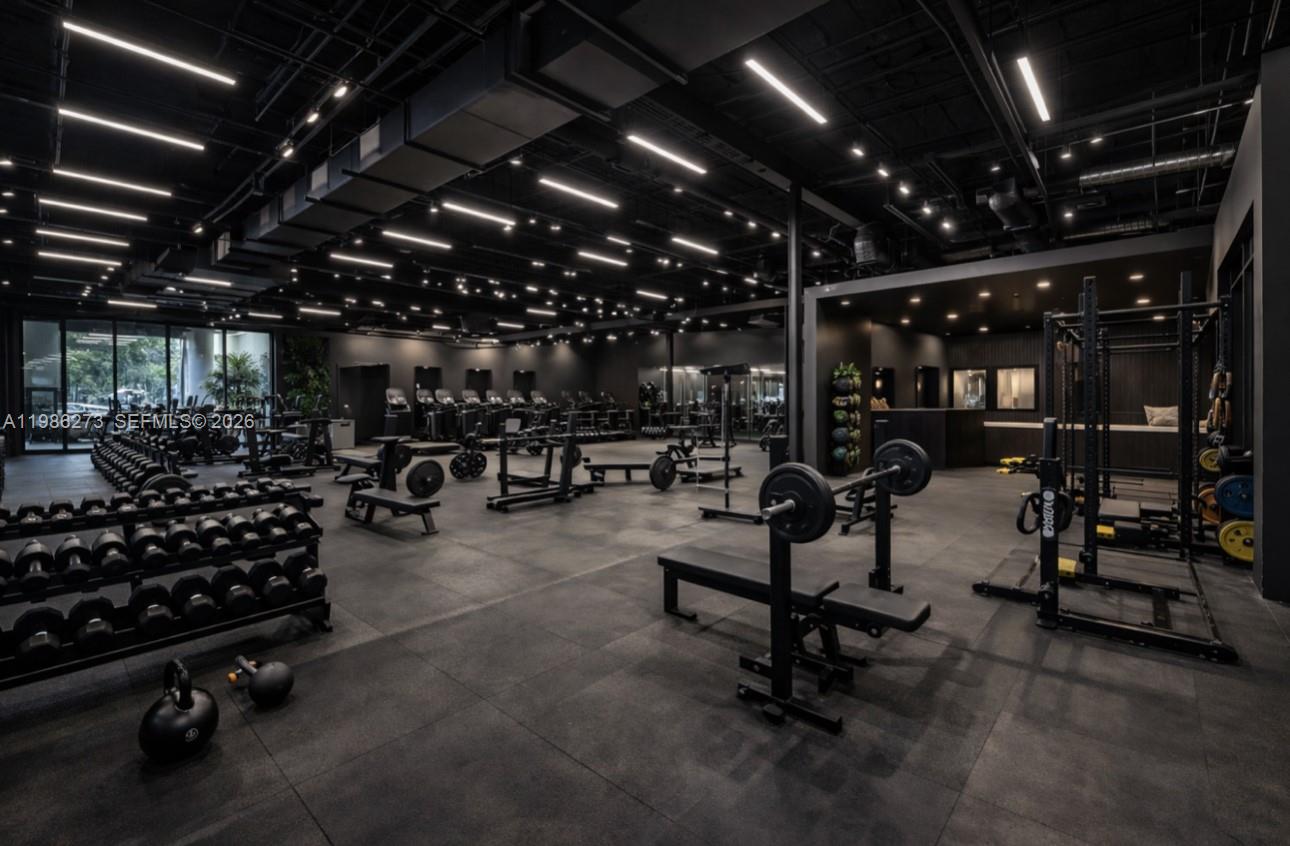 A modern, dark-themed gym features rows of dumbbells, weight benches, and various strength training equipment — 2950 N 28th Ter, Hollywood FL 33020, HOLLYWOOD, FL